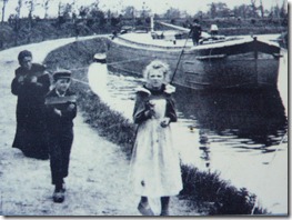 Humans hauling barge along tow path